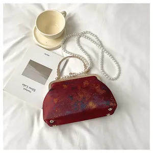 Detalle de bolso chino rojo con correa de perlas y asa metálica redonda vintage