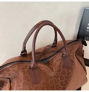 Detailed macro view of a large leopard print travel bag featuring sturdy brown leather handles