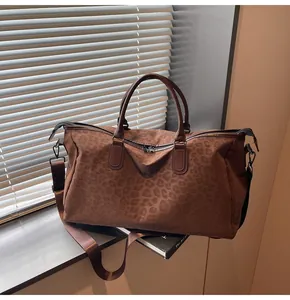 Large leopard print travel bag with brown handles on a window sill setting.