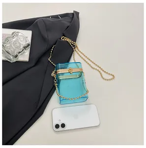 Blue transparent acrylic box bag with gold chain strap beside a smartphone