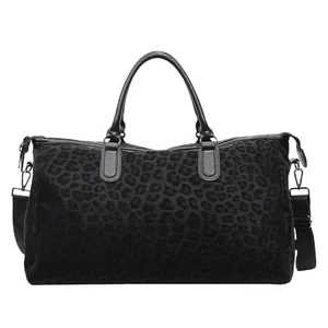 Front view of a large black leopard print travel duffle bag with adjustable shoulder strap