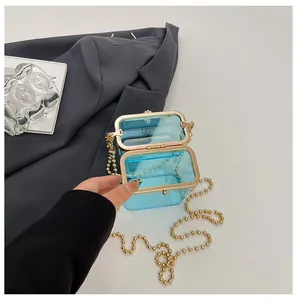 Detailed view of an open blue acrylic box bag with a golden ball chain strap.