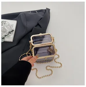 Close-up detail of a transparent purple acrylic box bag with golden beaded chain strap