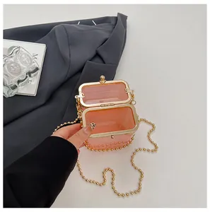 Close-up of the open interior of a pink acrylic box bag with a gold bead chain.