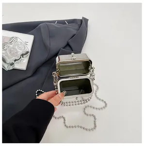 Detail view of an open silver metallic box bag with a beaded chain strap.