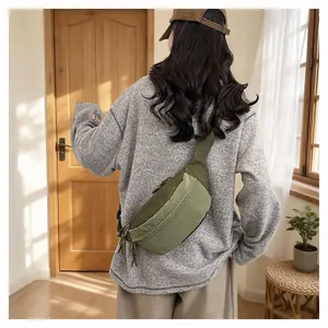 Back view of a woman wearing a green minimalist crossbody chest bag in a cozy room