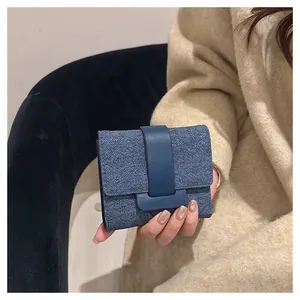 Close-up of stylish blue denim trifold wallet held by hand in lifestyle setting
