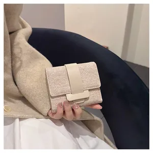 Close-up of a stylish textured fabric flap wallet held in hand for size perspective.