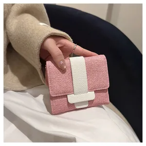 Close-up detail of a stylish pink textured fabric short wallet with contrast white buckle