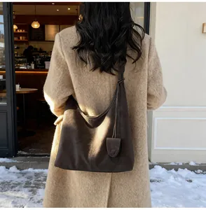 Back view of a vintage dark brown leather hobo shoulder bag worn with a beige winter coat