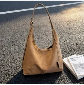 Detail view of a minimalist khaki faux leather hobo bag under natural sunlight