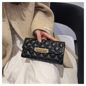 Detalle de una elegante cartera larga acolchada negra con un sofisticado cierre dorado
