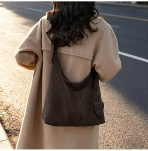 Minimalist vintage dark brown shoulder hobo bag shown being carried by a model outdoors
