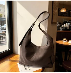 Minimalist vintage brown hobo shoulder bag displayed on a sunny cafe window sill