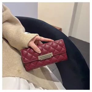 Detalle de una elegante cartera larga burdeos acolchada para mujer sostenida en la mano