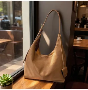 Elegant tan leather hobo bag resting on a wooden ledge in a sunlit cafe environment