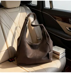 Minimalist dark brown leather hobo shoulder bag displayed on a luxury leather car seat