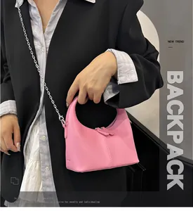 Close-up of a small pink PU leather handbag held by a model in a black blazer