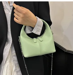 Close-up of a light green soft PU leather crescent handbag with a metal chain strap