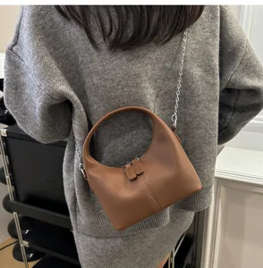 Minimalist brown soft PU leather handbag worn with a silver crossbody chain detail