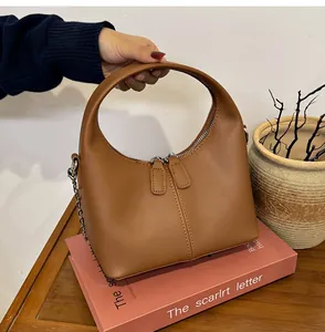 Vintage brown soft PU leather handbag showcased as detail view on a decorative book