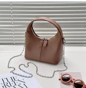Detailed view of a brown vintage PU handbag with a silver chain strap and sunglasses