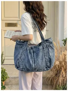 Detalle de un bolso tote grande de mezclilla azul para un look de estudiante casual.