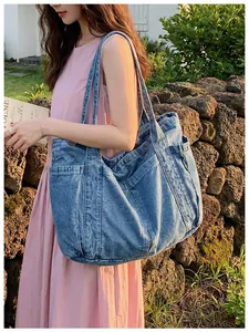 Vista detallada de un bolso tote de mezclilla azul informal llevado por una modelo.
