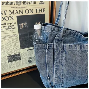 Detalle lateral de un bolso tote de mezclilla azul lavado con bolsillo exterior