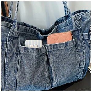 Detalle del bolso tote de mezclilla azul con dos bolsillos frontales y textura de tela