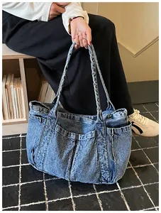 Detalle de un bolso tote de mezclilla azul con asas trenzadas y bolsillos externos