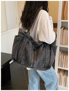 Bolso tote grande de mezclilla negra lavada para mujer en un ambiente interior informal