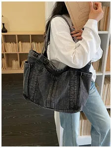 Primer plano de una estudiante cargando un gran bolso tote de mezclilla antracita en una biblioteca.