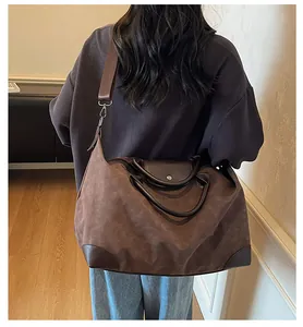 Detailed back view of a model carrying a large retro brown suede duffel travel bag