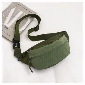 Detail view of a green grid-patterned lightweight crossbody chest bag on a white surface