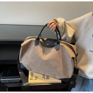 Large taupe suede travel bag with black leather handles and adjustable shoulder strap