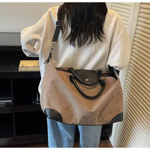 Detail view of a large brown frosted suede travel bag worn as a crossbody duffel