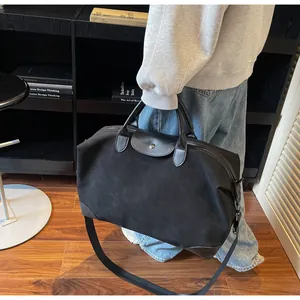 Large black frosted suede duffel bag for travel, shown held by a person in a library