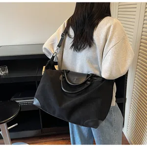 Large black frosted travel bag with leather handles shown on model in a stylish interior