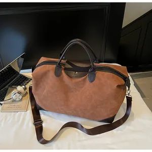 Lifestyle view of a vintage suede travel bag on a bed with headphones and laptop