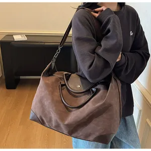 Detail view of a retro large brown suede travel bag worn as a stylish shoulder bag