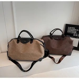 Close-up detail of vintage matte suede travel bags in khaki and brown with shoulder straps