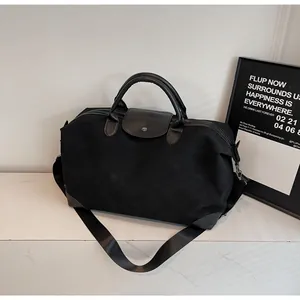 High-quality black matte suede travel duffle bag with leather handles and shoulder strap.