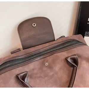 Detail of a high-quality brown suede travel bag with zipper and snap flap closure