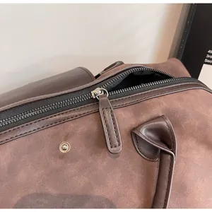 Close-up view of the durable metal zipper and suede texture on this retro brown travel bag.