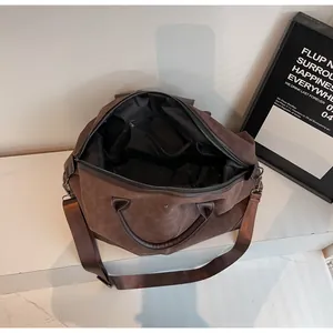 Macro view of the spacious black interior lining of this brown suede travel duffel bag.