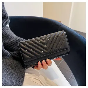 Elegante portafoglio lungo nero con motivo trapuntato a V e borchie dorate in mano