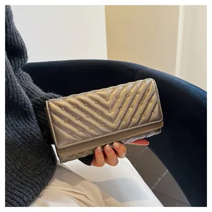 Dettaglio di un portafoglio metallizzato trapuntato a chevron con borchie dorate