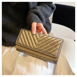 Primo piano di un portafoglio trapuntato oro metallizzato con cuciture a V e borchie