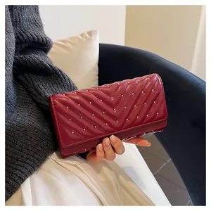 Primo piano di un elegante portafoglio lungo trapuntato bordeaux con borchie dorate a mano.